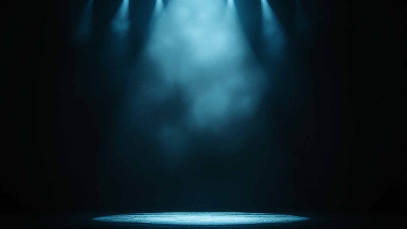 An empty stage with a single strand of holiday lights glowing against the dark, haze in the beam